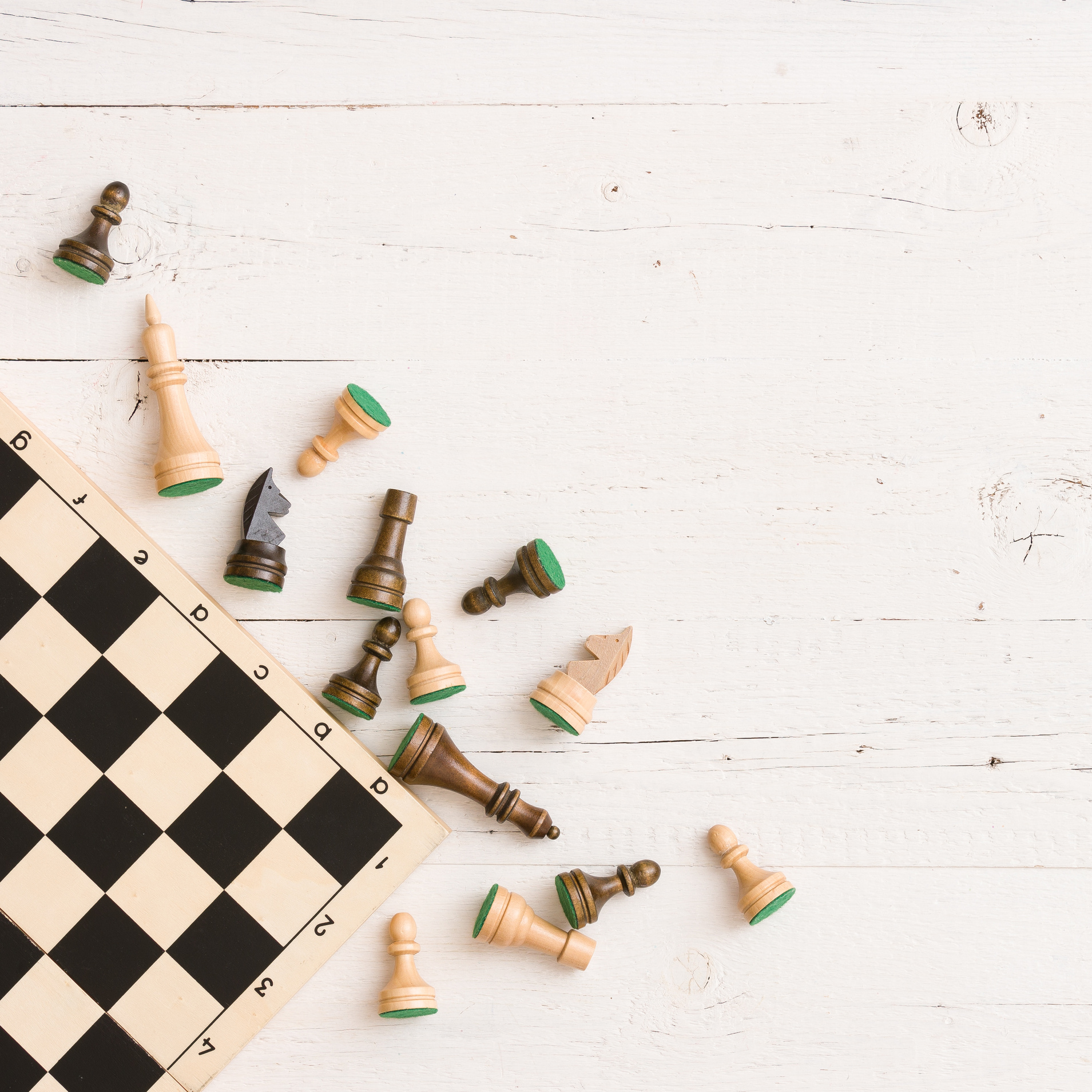 Wooden chess figures and chess board on white table background. Top view.